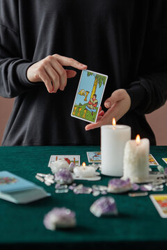 Female medium holding Four of Cups tarot card.