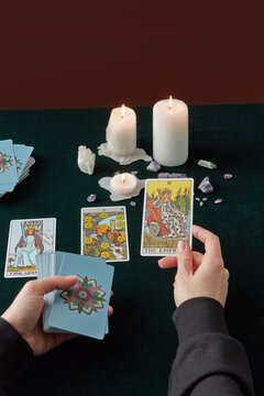Woman laying out tarot cards, burning candles beside.