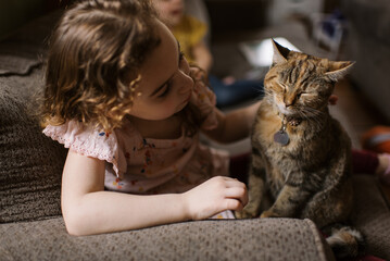 Girl petting her cat while sitting on couch 