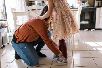 Mother helping her daughter put her shoes on