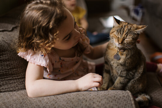 Girl petting her cat while sitting on couch 