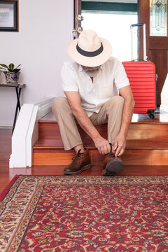 Man tying shoes in his foyer before leaving on a trip