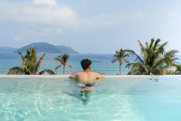 A man relaxing in an infinity pool overlooking the ocean