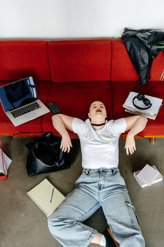 Student with short shaved hair resting leaning back on red sofa