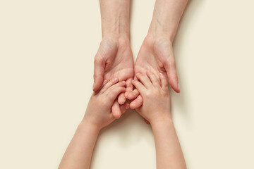 Tender mother's hands holding little kid's hands.