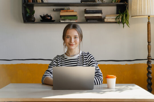 A woman smiles while sitting in front of a laptop