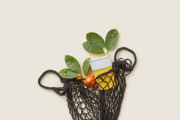 Tangerine and reusable cup in black string bag.