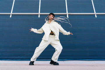 Stylish woman dancing with outstretched arms on street