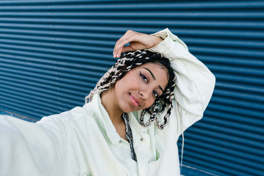 Dreamy stylish woman taking selfie against blue wall