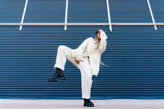 Confident woman dancing near blue building