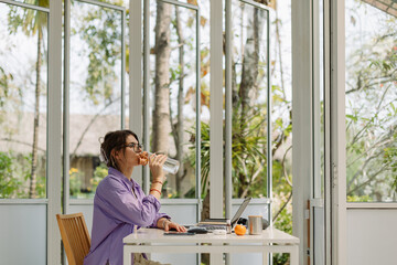 Woman drinking water while working at home office