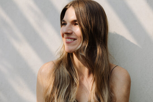 Smiling woman near white wall