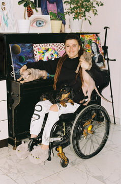 A girl in a wheelchair at home with two bald cats and a dog
