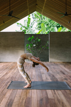 Female yoga instructor bending backwards while practicing at studio