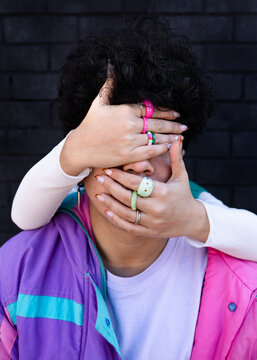 Hands with rings covering the face of a man