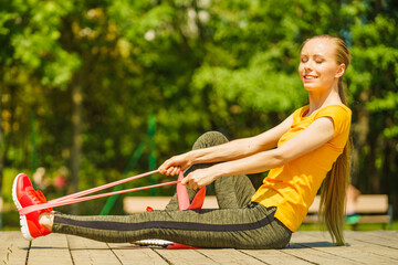 Girl doing exercise outdoor, using resistance fit band.