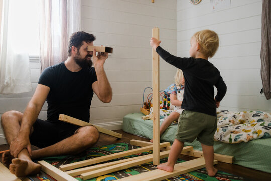 Dad peering through pretend binoculars at his children 