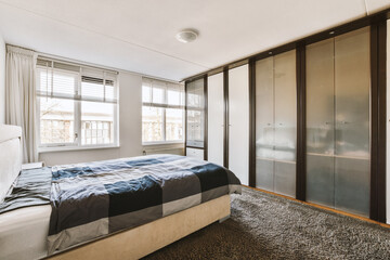 a bedroom with a bed and wardrobes in the corner, there is a large mirror on the wall behind it