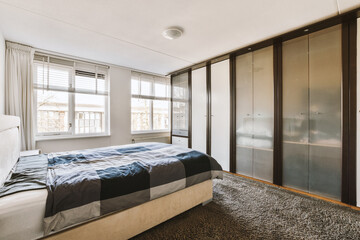 Obraz premium a bedroom with a bed and wardrobes in the corner, there is a large mirror on the wall behind it