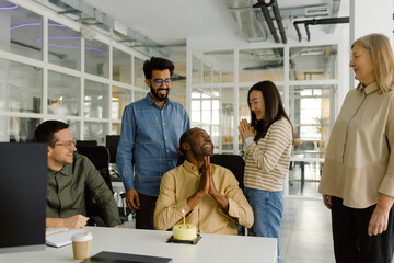 Diverse coworkers enjoy cake anniversary party 