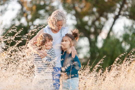 Grandmother and grandchildren embraced in golden grass