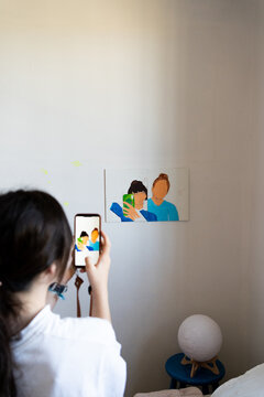 Girl taking pictures of her drawing at bedroom