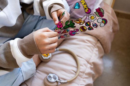 Faceless girl customizing headphones with stickers 