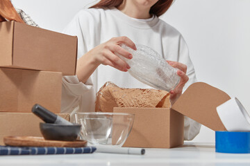 Unrecognizable woman wrapping kitchenware in packaging.