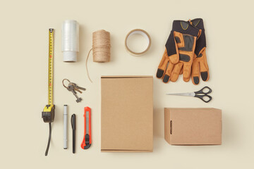 Cardboard boxes and various tools on beige background.