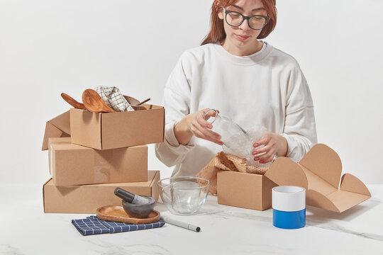 Woman wrapping glassware in protective packaging.