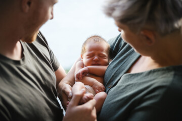 Sleeping baby with parents holding.
