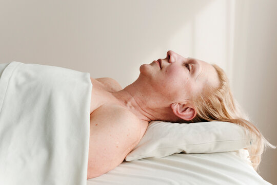 Senior relaxed woman lying on massage table in spa.