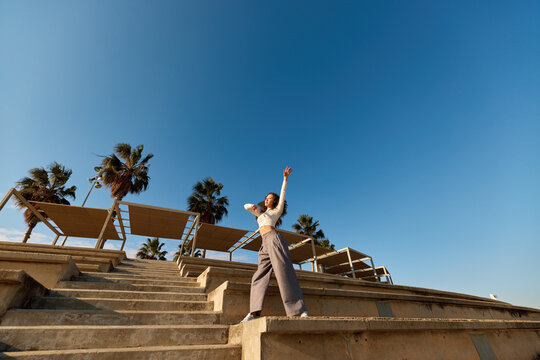 Young Asian lady listening to song and dancing in park