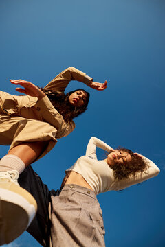Stylish diverse ladies under cloudless blue sky