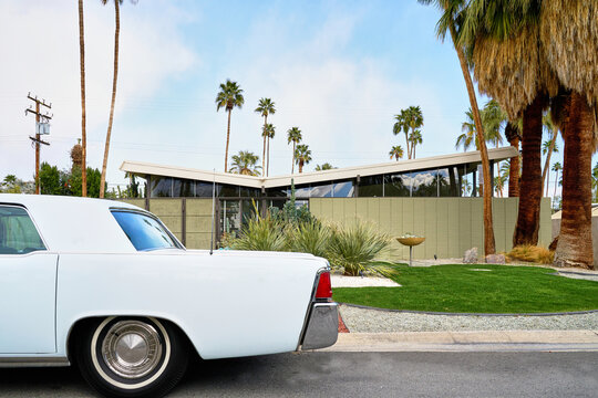 Vintage car parked on road in front of mid century modern home