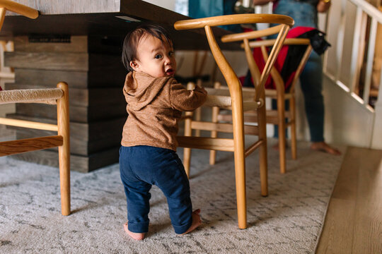 Adorable asian baby boy learning to pull himself up on furniture