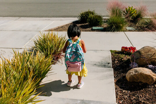 Preschool child wearing a backpack on the way to the car