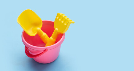 Plastic toys, shovels in bucket on blue background. Summer background concept