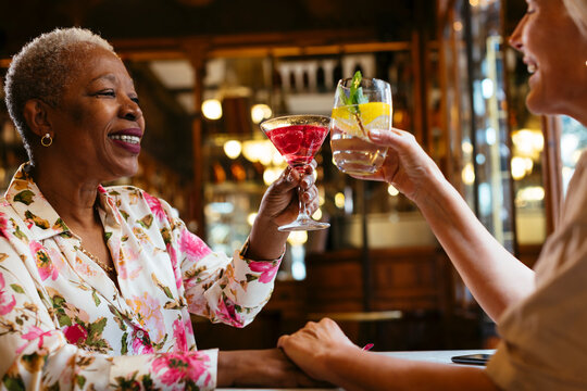 Happy best friends clinking glasses in cafe