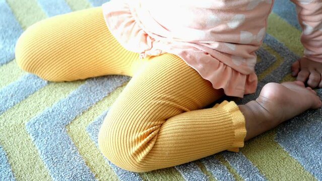  child sitting W posture on the floor .