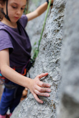 rock climber's hand close-up. child rock climber in a blue protective helmet overcomes the route in the mountains. children's sports in nature.
