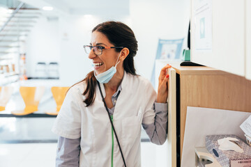 Happy woman in medical uniform looking away in clinic