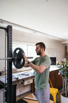 Visually impaired man adjusting weights on bar.