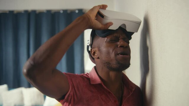 Irritated multiracial men in VR headsets hit the wall with hands, yell at each other through thin walls. Neighbours quarrel. Apartment without sound insulation. Concept of neighbourhood and lifestyle.