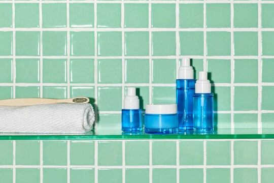 Makeup supplies for skin care placed on glass shelf in modern bathroom