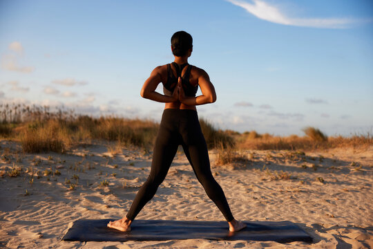 Anonymous woman performing yoga pose on sandy beach
