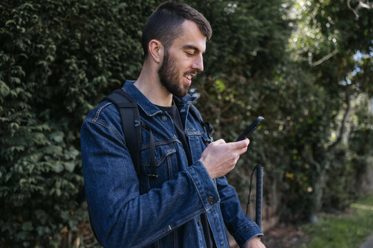 Man using his phone on the sidewalk bus stop.