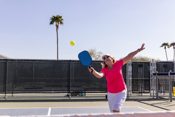 Fun Senior Citizen Pickleball player looks to swing at ball 