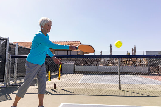 Senior Citizen Pickleball player serving yellow ball  match 