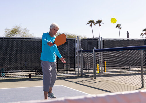 Senior Citizen Pickleball player backhand swing hitting ball in match 